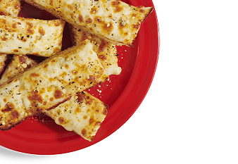 A red plate stacked with slices of garlic cheesy bread.