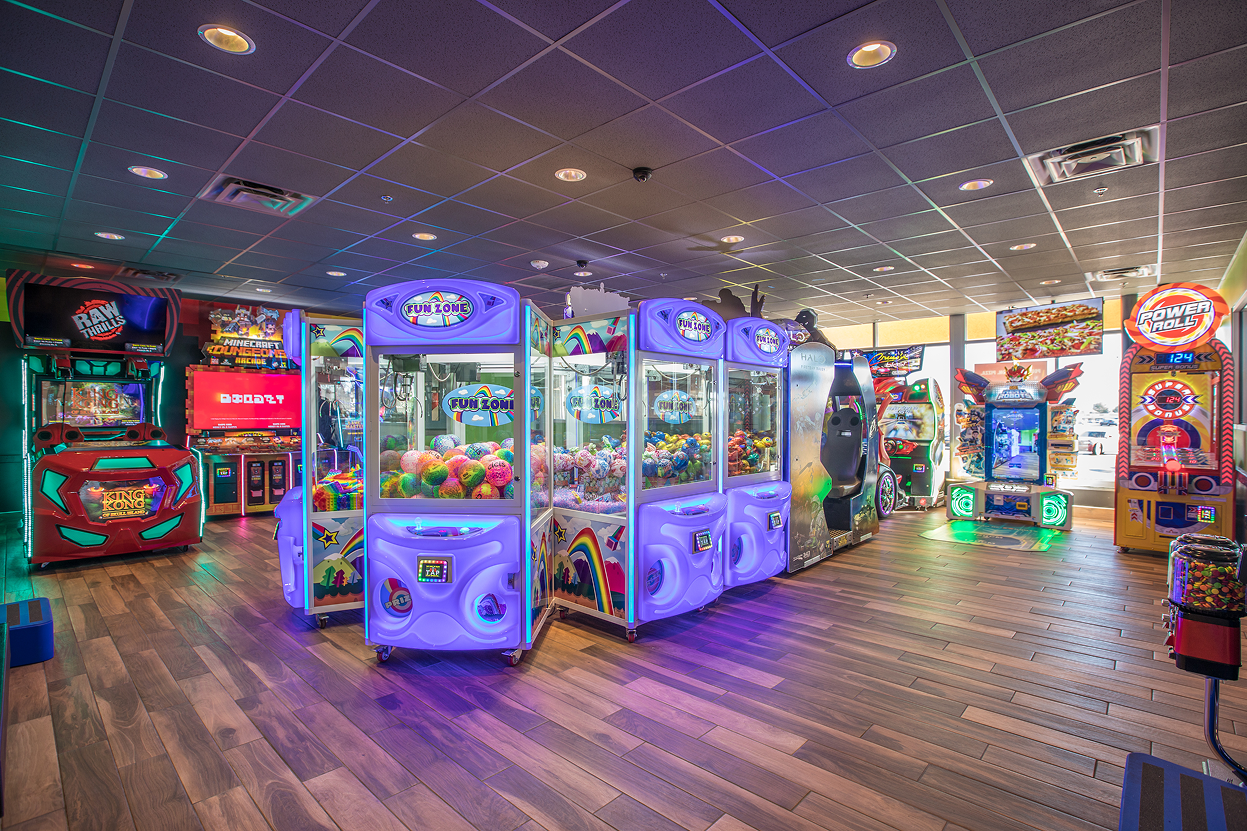 Cicis Game Zone filled with lit up arcade cabinets, "Fun Zone" labeled claw prize machines, and car racing games.